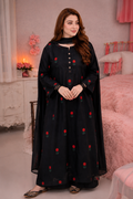 A woman wearing a black long kurta with red rose embroidery and a matching black dupatta, standing in a pink bedroom setting.