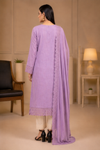 A woman shown from the back wearing a lavender purple traditional kurta set with a matching dupatta, cream pants, and black heels in an indoor setting.