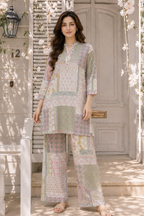 A woman stands on a porch wearing a pastel patchwork-print kurta and wide-leg pants set. The outfit features a mix of soft pink, sage green, beige, and light blue geometric and floral patterns.